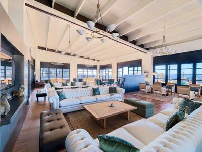 Spacious hotel lounge with modern sofas, large windows, and a wooden beamed ceiling.