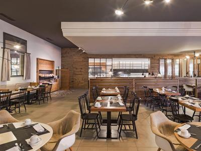 Spacious hotel restaurant with modern decor, wooden floors, and well-arranged tables and chairs.