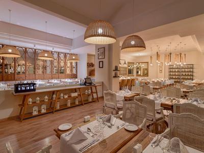 Cozy restaurant with wooden floors, wicker chairs, warm lighting, and a stylish bar area.