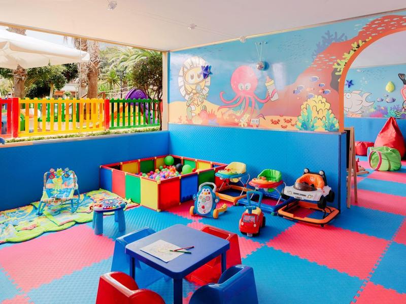 Colorful kids playroom with toys, soft mats, and seating, ideal for children at a hotel or resort.
