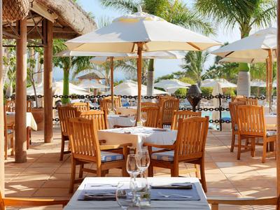 Venkovní restaurace s dřevěným nábytkem a slunečníky v tropickém dovolenkovém místě.