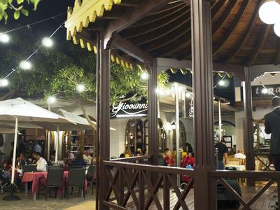 Beleuchteter Außenbereich mit Sitzplätzen, Bäumen und Pavillon bei Nacht.