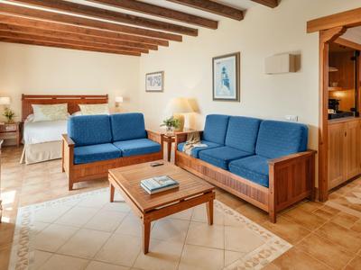 Pohodlný hotelový pokoj s modrými pohovkami, dřevěným nábytkem a postelí v pozadí.