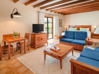 Pohodlný obývací pokoj s dřevěným stropem, dvěma modrými pohovkami, dřevěným nábytkem a terasou s výhledem na zeleň.