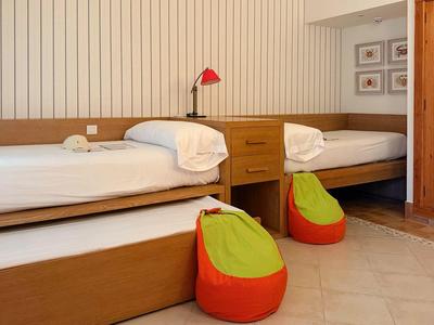 Dvoulůžkový pokoj s dřevěným nábytkem, bílými postelemi a barevnými sedacími pytli na podlaze.