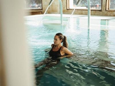 Frau entspannt in einem Innenpool mit Fensterlicht und Wasserdüsen.