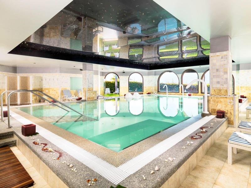 Piscine intérieure avec chaises longues et grandes fenêtres dans un hôtel moderne