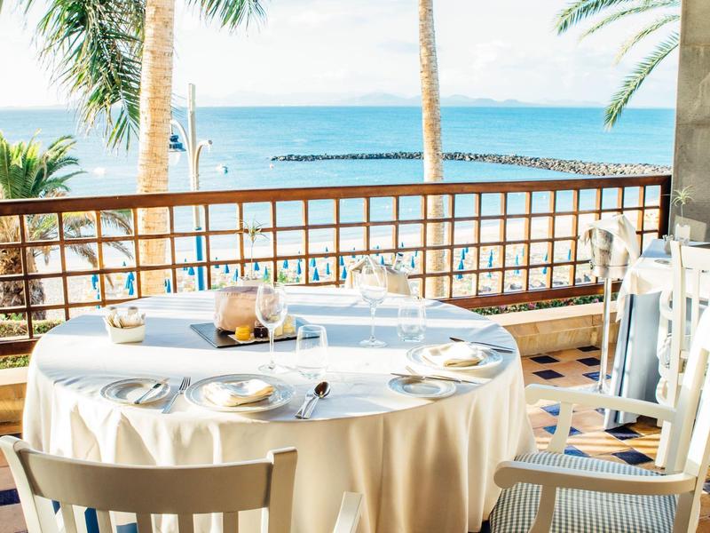 Espace repas en extérieur avec table dressée et vue sur la mer par beau temps