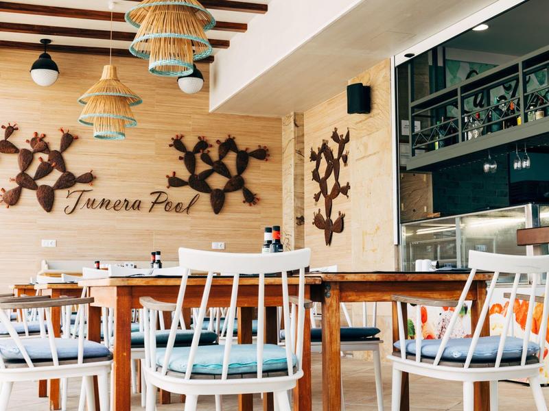 Restaurant moderne avec tables en bois, chaises blanches et décorations murales en bois.