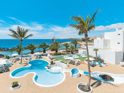 Modern hotel pool with palm trees and sea view under blue sky