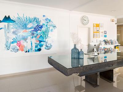 Reception moderna dell'hotel con arte murale e elegante banco accoglienza scuro.