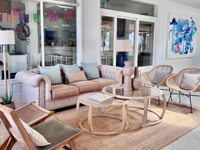 Modern lounge area with sofas, armchairs, and glass table in a bright room.