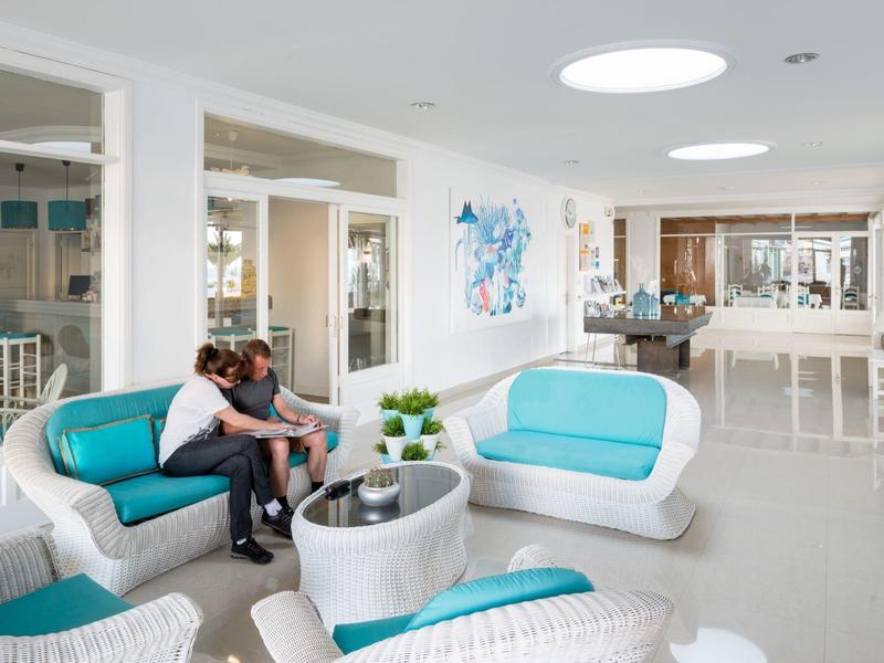 Bright hotel lobby with modern white and turquoise seating and a couple sitting on the sofa.