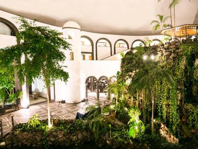 Lit indoor courtyard with plants and arched windows in a hotel.