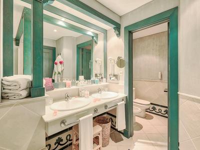 Světelná koupelna se dvojitými umyvadly, velkým zrcadlem a vanou.