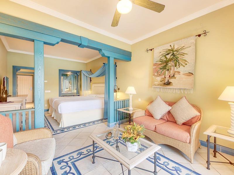 Útulný hotelový pokoj s pohovkou, postelí a elegantním zařízením v jemných tónech.