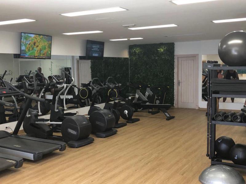 Moderní posilovna s běžeckými pásy, jízdními koly, eliptickými stroji a medicinálními míči na dřevěné podlaze.