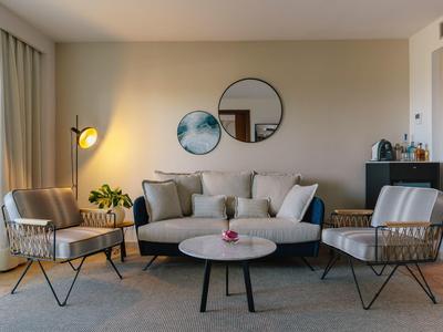 Zona giorno moderna con poltrone chiare, divano, specchi rotondi e tavolino.