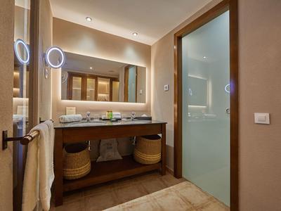 Bagno moderno con grande specchio, lavabo, illuminazione e doccia in vetro.