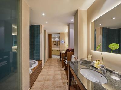 Bagno moderno con lavabo, grande specchio e accesso alla camera da letto.