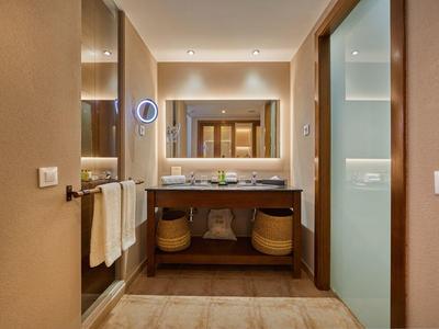 Moderno lavabo da bagno in hotel con specchio, asciugamani e articoli da toilette con luce calda.