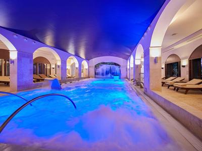 Piscina cubierta con techo iluminado en azul y tumbonas en un hotel de lujo.