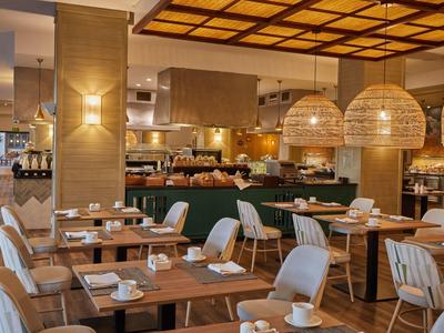 Ristorante moderno con mobili in legno e luce calda da grandi lampade rotonde.