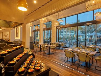 Ristorante moderno con pavimento in legno, grandi finestre e buffet con piccoli piatti.