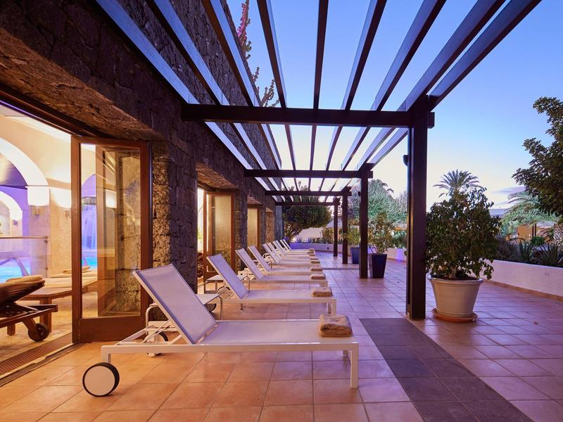 Terrazza con lettini accanto a un'area spa in un hotel al crepuscolo.