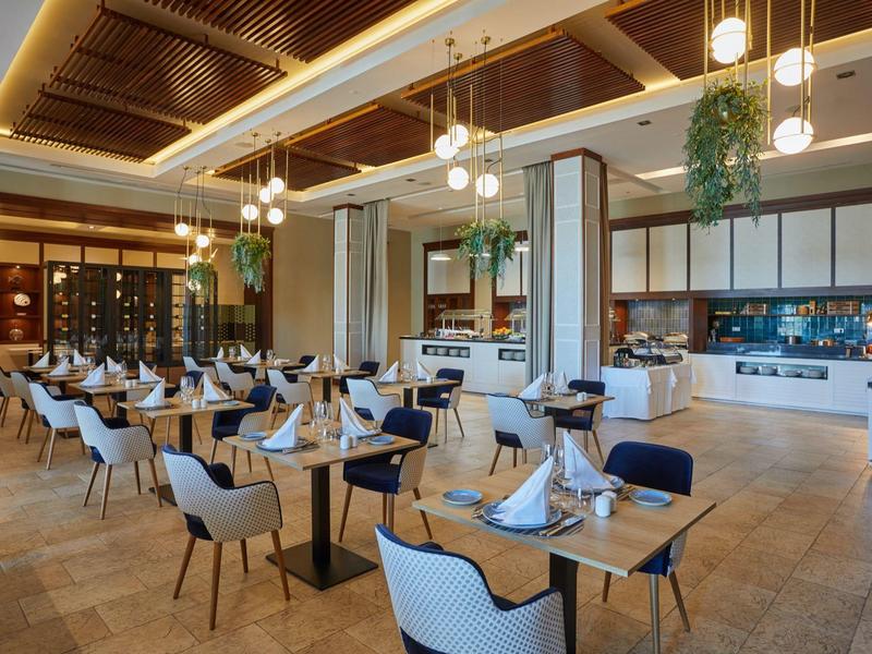 Elegante ristorante d'hotel con design moderno, tavoli apparecchiati e luce calda.