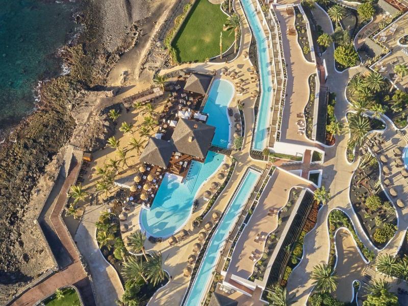 Vista aerea di un hotel di lusso con diverse piscine lungo una costa rocciosa.