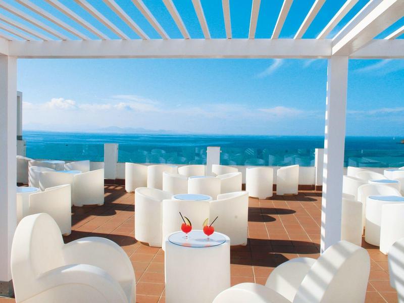 Witte buitenlounge met zeezicht en twee drankjes op een zonnige dag.