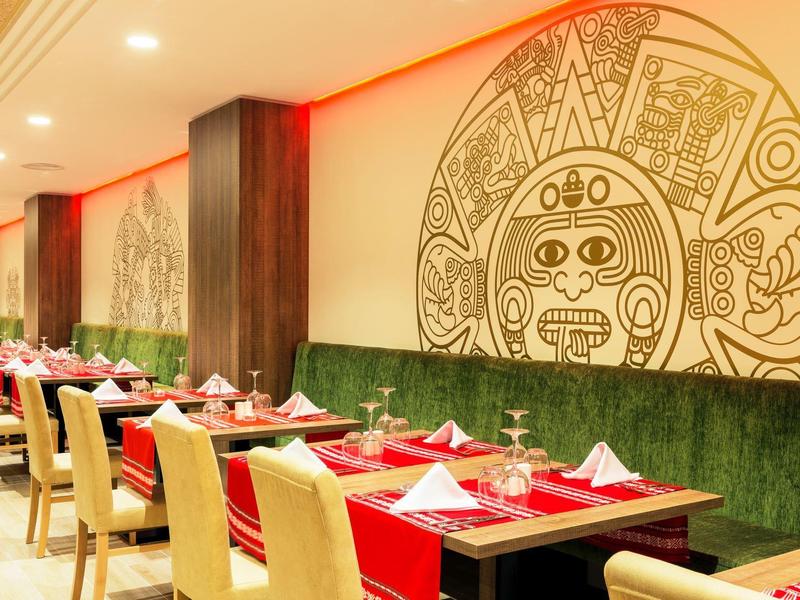 Hotel eetruimte met artistieke octopus muurdecoratie, houten tafels en crèmekleurige stoelen.