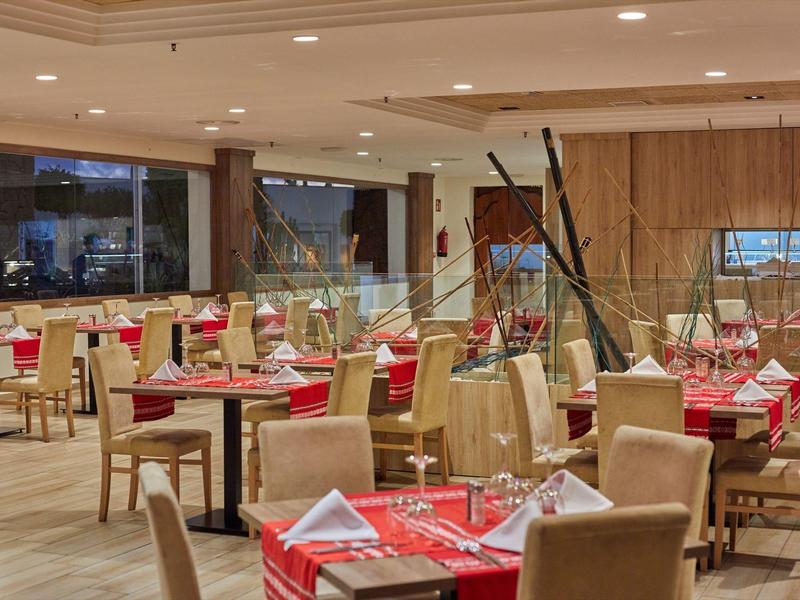 Ruim restaurant met elegante tafels gedekt met rode servetten en wijnglazen.