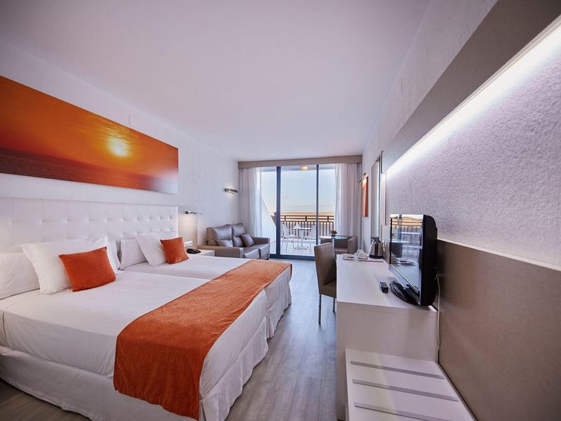 Moderne hotelkamer met tweepersoonsbed, oranje accenten, balkon en tv.