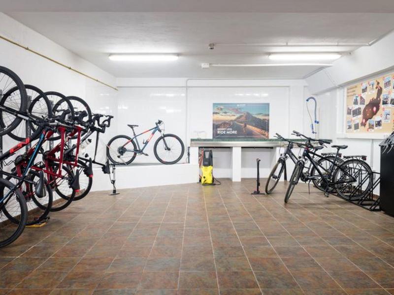 Fietsenstalling binnen met meerdere fietsen aan rekken en betegelde vloer