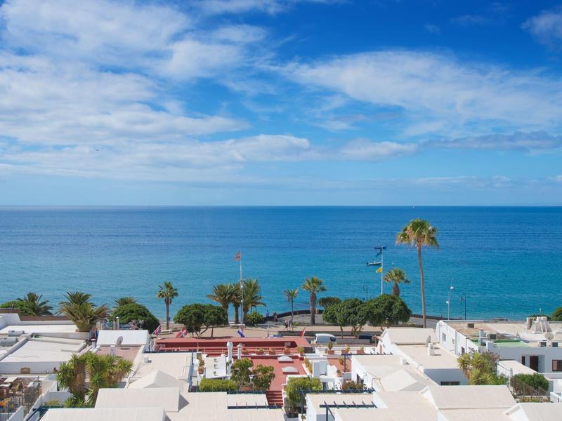 Vista sul mare azzurro e edifici bianchi sotto un cielo nuvoloso
