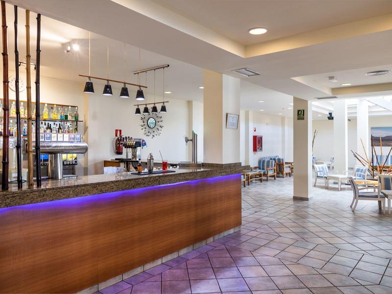 Area reception moderna di un hotel con banco illuminato di blu e aree salotto