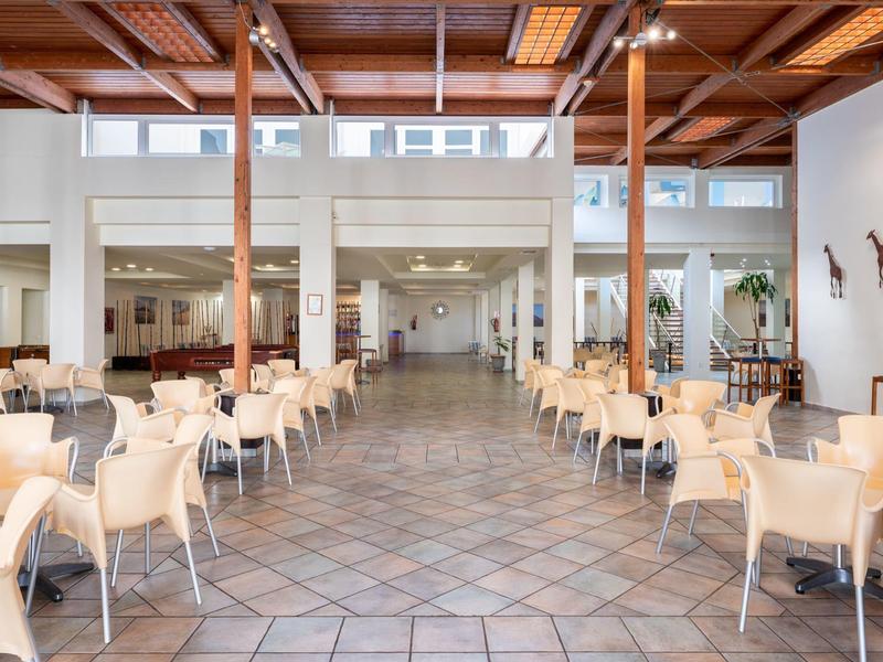 Ampia sala ristorante dell'hotel con molta luce naturale e file di tavoli e sedie.