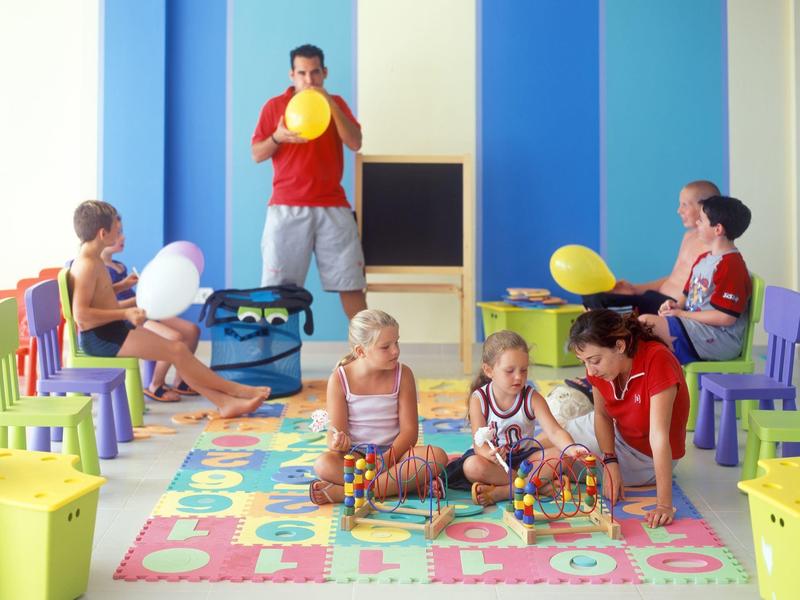 Bambini giocano con palloncini e giocattoli in una stanza colorata con pareti blu.