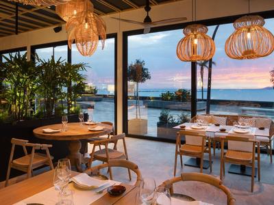 Ristorante moderno con grandi finestre e vista sul mare al tramonto