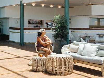 Lounge luminosa con poltrone comode, divani e una donna che si rilassa in una giornata soleggiata.