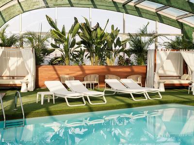 Piscina interna con lettini e piante tropicali sotto una copertura verde