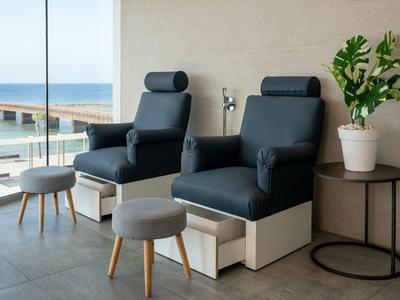 Due poltrone in pelle nera con poggiapiedi e un tavolino accanto a una finestra con vista sul mare.