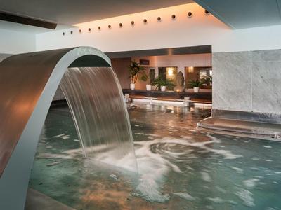 Piscina interna moderna dell'hotel con cascata e atmosfera rilassante.
