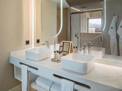 Mobile bagno moderno in hotel con due lavandini, grandi specchi e asciugamani.