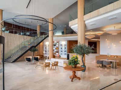 Luminosa hall d'hotel con pavimento in marmo, scala moderna e aree salotto.