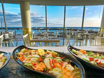 Buffet con frutti di mare freschi davanti a una finestra panoramica con vista sul mare.