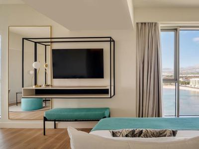 Camera d'hotel moderna con vista mare, TV, tavolo e balcone