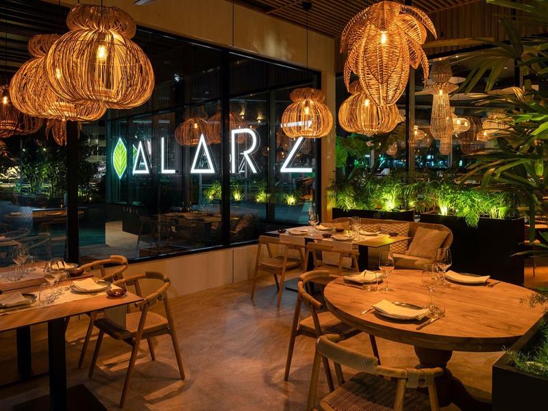 Ristorante accogliente con luce calda, mobili in legno e parete verde la sera.